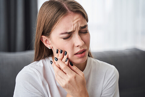 Woman holding hand agaist sore mouth